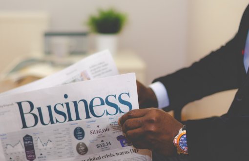 ręce trzymające gazetę z napisem "business" 