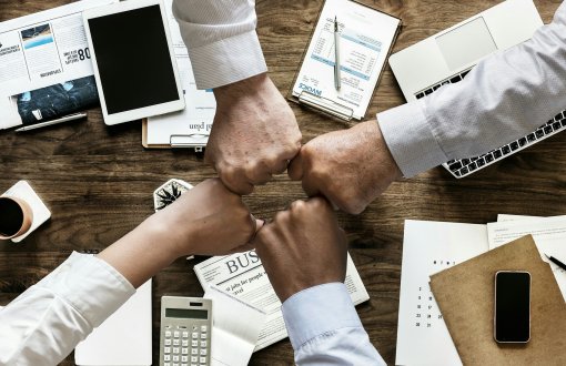 grupa ludzi z rękami w pięści trzymających się razem